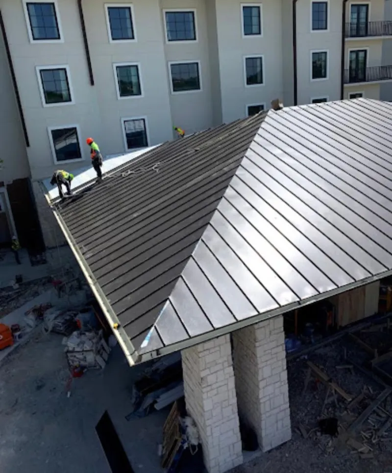Crew installing standing seam metal roof panels on a commercial project in Franklin